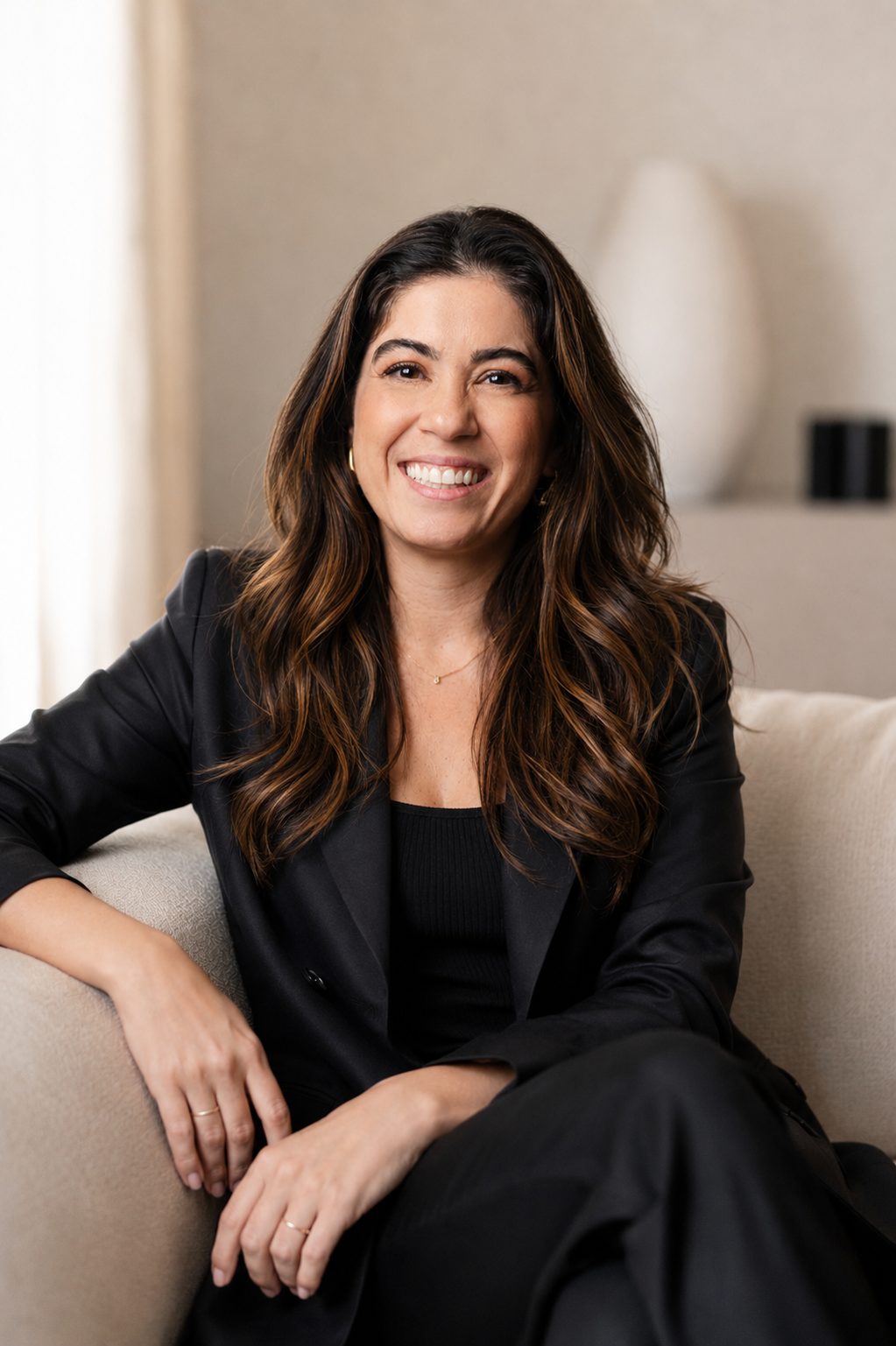 Erika Fernandes, mentora estratégica de vendas, sorrindo em um sofá claro